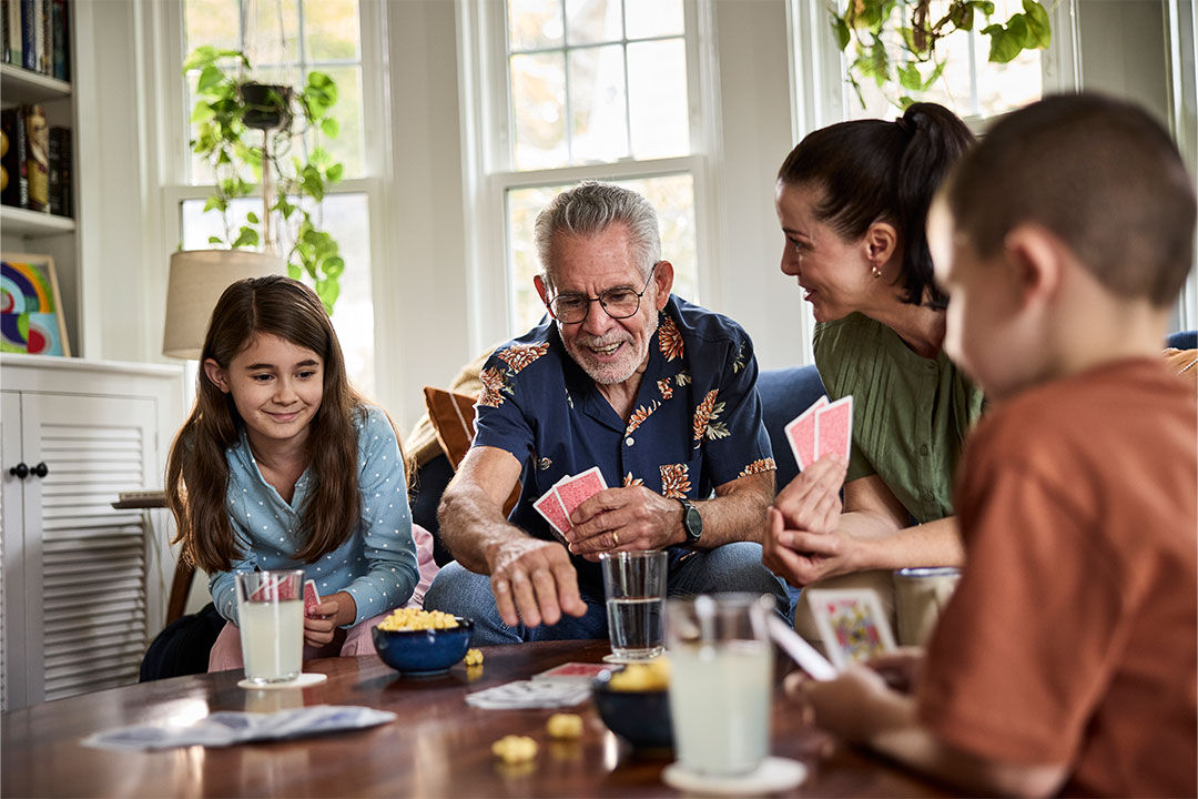 Group of adults and children playing cards.